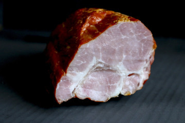 .smoked juicy meat - ham with golden crust isolated on a dark background