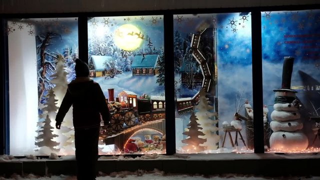 Boy, looking through a window in shop, decorated for Christmas holidays