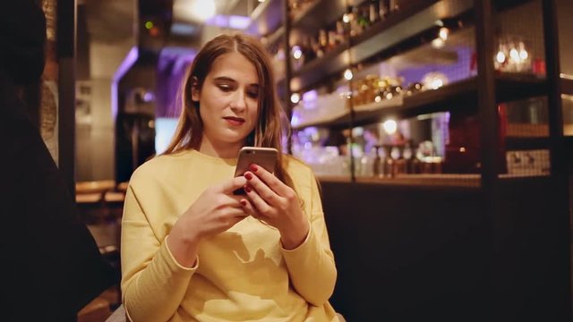 Young caucasian girl at restaurant texting on the smart phone