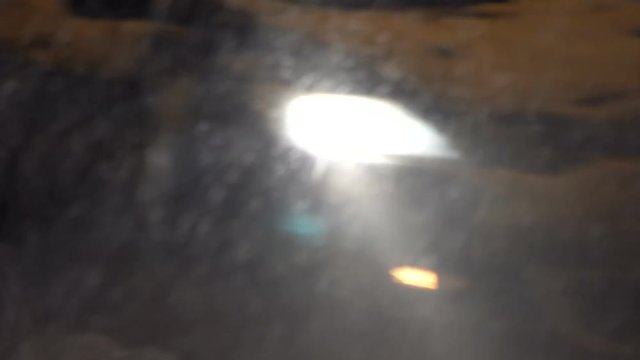 Close-up of a night traffic moving in a snowfall. Headlights in Winter storm.