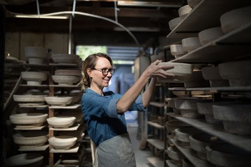 Female potter placing bowl in shelf