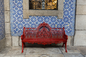 red iron bench in front of a church covered in tile, Porto, Portugal