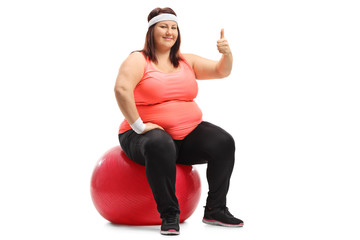Overweight woman sitting on a pilates ball and making a thumb up sign