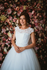 beautiful bride on the background of a wall of flowers