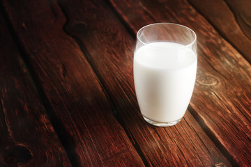 Glass of fresh milk on old wooden background.