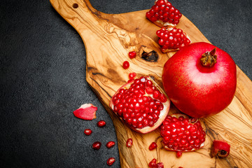 Pomegranate and seeds close-up on dark concrete background