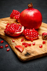 Pomegranate and seeds close-up on dark concrete background