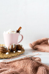 Fototapeta na wymiar Cup of hot chocolate and marshmallows with cakes. Knitting from rose yarn on a white background