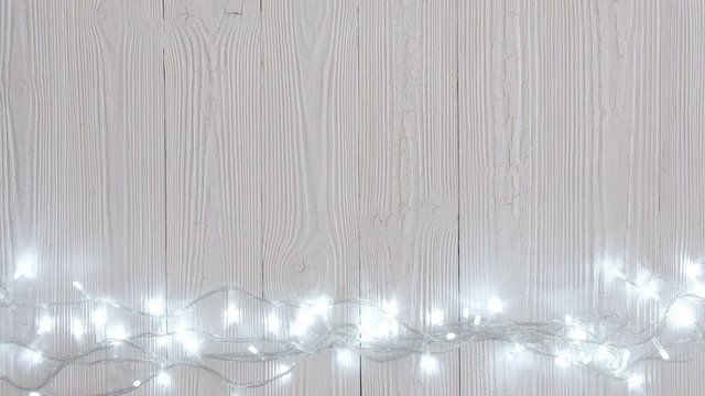 Fancy blinker light bulbs or garlands and wreath on wood table for Christmas or New years decoration background, Christmas colorful glowing lights border celebrate, add text or picture. 4K, UHD.