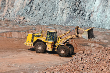 Earthmover in an active quarry mine of porphyry rocks. digging.
