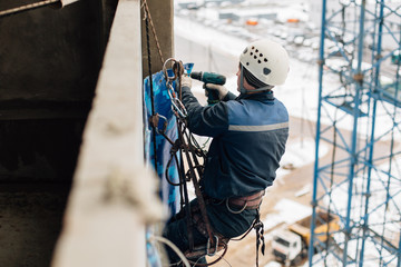 Professional industrial climber in helmet and uniform works at height. Risky extreme job....