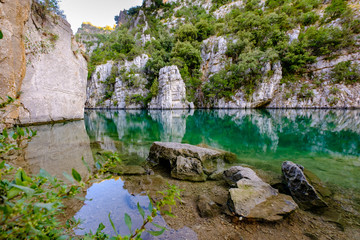 Fototapeta na wymiar Basses Gorges du Verdon, Quinson en été, beau reflet des arbres et rochers dans l'eau calme. Provence, France. 