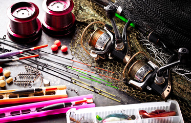 Fishing rods and spinnings in the composition with accessories for fishing on the old background on the table