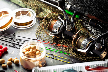 Obraz na płótnie Canvas Fishing rods and spinnings in the composition with accessories for fishing on the old background on the table