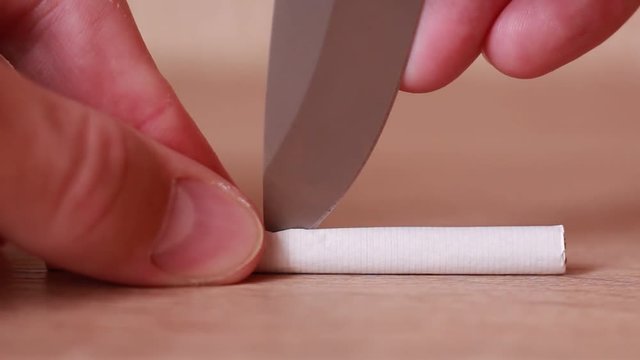 Cutting cigarette by knife closeup