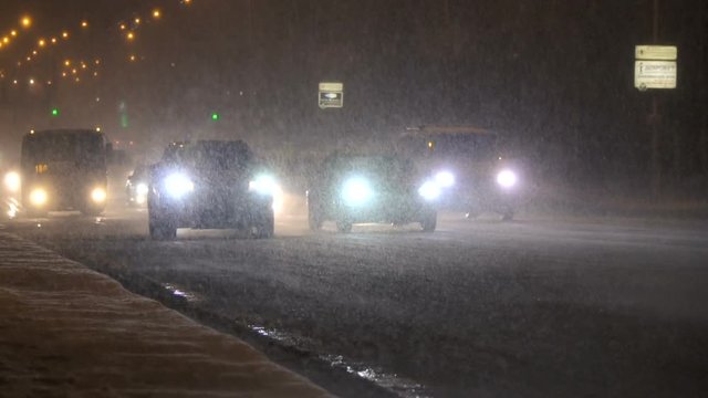 Night traffic moving in a snowfall. Winter storm.