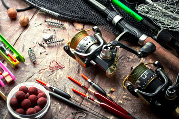 Fishing rods and spinnings in the composition with accessories for fishing on the old background on the table