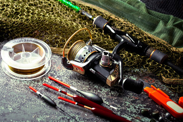 Fishing rods and spinnings in the composition with accessories for fishing on the old background on the table