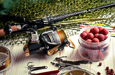 Fishing rods and spinnings in the composition with accessories for fishing on the old background on...