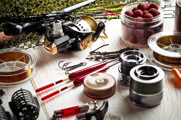 Fishing rods and spinnings in the composition with accessories for fishing on the old background on the table