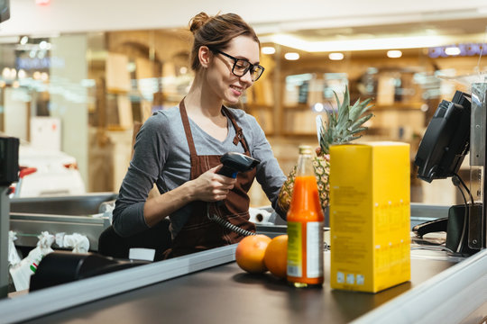 Smiling female cashier scanning grocery items