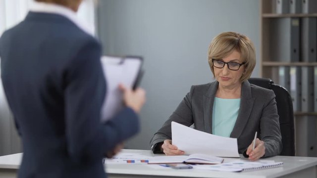 Irritated lady manager deciding what to do with office trainee, poor performance