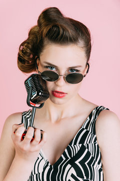 Girl in glasses sing in microphone.