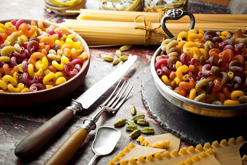 Raw pasta in the composition on the table with items for cooking