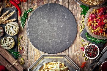 Raw pasta in the composition on the table with items for cooking