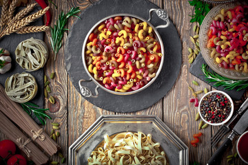 Raw pasta in the composition on the table with items for cooking