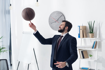 side view of young businessman in suit playing basketball in office