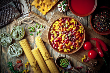 Raw pasta in the composition on the table with items for cooking