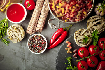 Raw pasta in the composition on the table with items for cooking