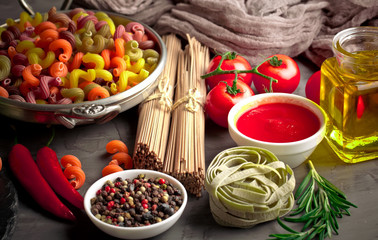 Raw pasta in the composition on the table with items for cooking