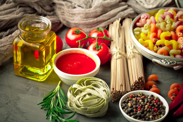 Raw pasta in the composition on the table with items for cooking