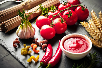 Raw pasta in the composition on the table with items for cooking