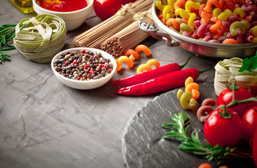 Raw pasta in the composition on the table with items for cooking
