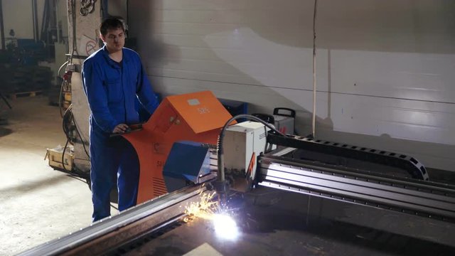 Factory worker control process cutting metal sheet with in metalworking computer