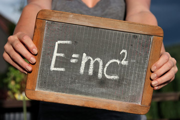theory of relativity written with chalk on slate shown by young female