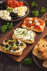 Variety of sandwiches with tomatoes, mozzarella, avocado, eggs and cream cheese.