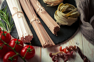 Raw pasta in the composition on the table with items for cooking