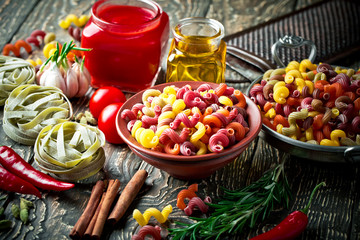 Raw pasta in the composition on the table with items for cooking
