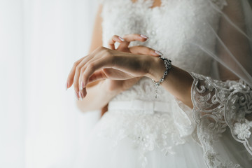 Bride wearing jewelry on hand in the morning on the wedding day.