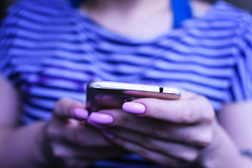 The girl in the striped shirt is typing on a mobile phone. No face. Soft focus. The background substrate.