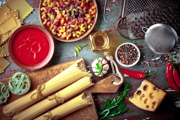 Raw pasta in the composition on the table with items for cooking