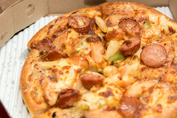 Close up of pizzas with variety of toppings and cheese in cardboard take out boxes with open lid