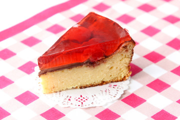 served slice of fresh baked delicious cherry cheese cake with cherry topping and decorated with chocolate on checkered tablecloth