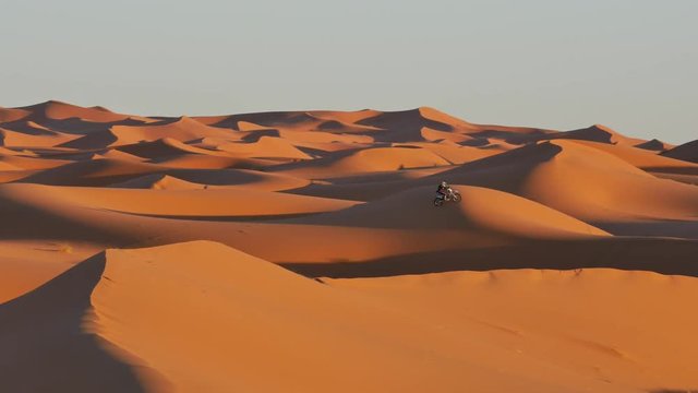 Off road motorcycle driving through the sand dunes of the desert of Morocco