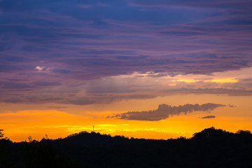 The silhouette of the landscape during the sunset on a summer evening, a bright orange light makes its way between the thick blue clouds. Cloudscape in Adler, Sochi, Russia.