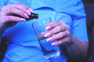 A young girl, the nurse puts drops in a glass of water. The treatment of poisoning.